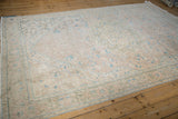 Angled view of a vintage distressed Sparta carpet with a faded blush and blue floral pattern.