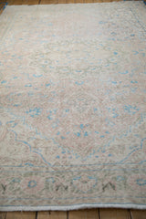 Angled view showing the distressed weave and soft colors of a vintage Sparta carpet.