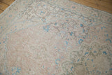 Detailed view of the distressed pile, showing exposed knot heads amid blush and blue florals.
