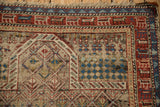 Antique Caucasian rug close-up, revealing exposed foundation, geometric field, and stylized animal border.
