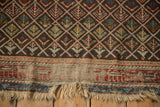 Tattered fringe and worn foundation on antique Caucasian geometric rug's border.