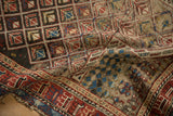 Antique Caucasian rug close-up: tattered edge, cherry red border, and exposed foundation.