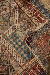Antique Caucasian rug with significant wear revealing geometric patterns and foundation.