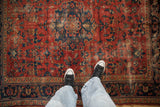 Worn vintage Lilihan rug with cherry red field, navy blue floral patterns, and visible foundation.