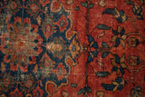 Vintage Lilihan rug's cherry red field with navy floral motifs and visible foundation wear.