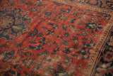 Vintage Lilihan rug detail: red field, navy floral blossoms, interconnecting vinery, and aged wear.