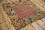 Tattered corner of antique Caucasian geometric rug, revealing colorful pinwheel motifs and foundation wear.