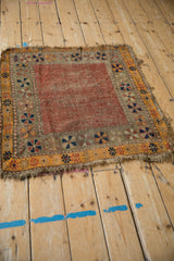 Corner detail of an antique Caucasian rug, showing ruby red field, navy, tangerine, and beige pinwheel borders, and natural wear.