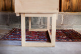 Low-angle view of the handmade sidecar's white maple base resting on a Persian rug.