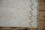 Ivory plain-weave hemp kilim rug with jet black zigzag stitching and bound edge.