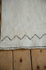 Beige plain-weave kilim with black zigzag added stitch detail and fringe.