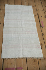 Textured hemp kilim weave with platinum, ivory, and pink horizontal stripes, showing fringe.