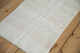 Vintage hand woven Hemp Kilim rug texture, ivory with soft blush stripes and fringe detail.