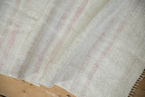 Textured hand-woven hemp kilim rug with faint rose stripes and machine-bound edge.
