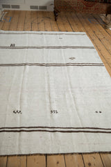 Primitive dark brown gul motifs and horizontal stripes on a neutral vintage kilim.