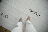 A view of the ivory plain-weave texture and dark stitched diamond accents on a vintage hemp kilim.