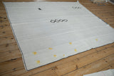 Full angled view of a vintage hemp kilim with minimalist black and yellow stitched accents.