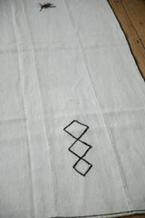 Stitched black diamond motif and a spider-like yarn tuft on a vintage hemp kilim.