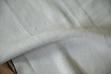 A soft fold showing the plain-weave texture and hand-seamed panels of a vintage hemp kilim.