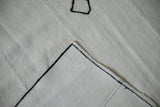 Turned corner of a vintage hemp kilim showing its textured plain-weave and black machine-bound edge.