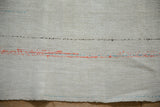 The textured plain-weave of a hemp kilim with bright orange and turquoise accent lines.