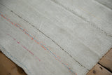 Textured weave of a vintage hemp kilim with colorful accents and a hand-stitched seam.
