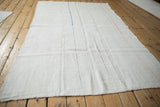 Angled view of a vintage hemp kilim showing its seamed construction and colorful accent stripes.
