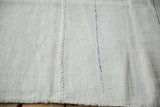 Hand-stitched seam and cobalt blue accent on a vintage hemp kilim's plain-weave surface.