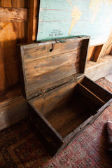 Open antique primitive black wooden trunk with distressed chippy paint and empty interior.
