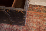 Close-up of the antique primitive wooden trunk's chippy black paint and distressed texture.