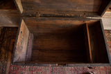 Interior of antique primitive black trunk showing distressed wood and a partition.