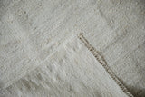 Neutral hand-woven Turkish hemp kilim's plain-weave texture and machine-bound edge.