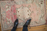 Distressed vintage Oushak rug with rose and silver tones, shown on the floor for scale.