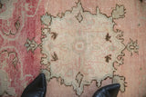 The evenly worn pile of a distressed Oushak rug showing its serrated starburst medallion.