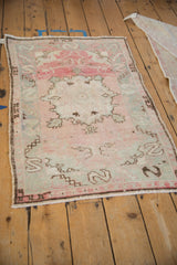 Angled view of a distressed Turkish Oushak rug showing its time-softened rose and silver colors.