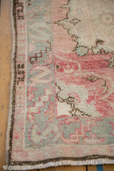Oversized serpent main border on a distressed Oushak rug in rose, silver, and brown, showing even pile wear.