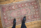 Vintage distressed Oushak rug displaying faded plum, slate blue, and brown geometric-floral medallions with feet.