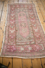Close-up of distressed vintage Oushak rug's faded plum geometric-floral pattern and worn pile.