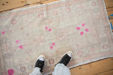 In-situ view of a vintage distressed Oushak rug with soft blush and bold magenta florals.