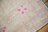 Low pile texture of a vintage Oushak rug showing magenta florals and a dusty blush geometric border.