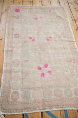 Angled perspective of a vintage Turkish Oushak rug with time-softened wear and pops of magenta color.