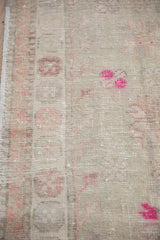 Even wear to the knot heads on a vintage distressed rug with dusty blush and magenta details.