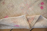 Folded corner of a vintage Oushak rug showing the hand-knotted back and distressed pile.