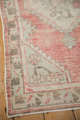 Distressed Oushak runner corner, faded raspberry, sea foam, charcoal geometric floral motifs.