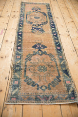 Distressed Oushak runner border showing faded blue, pink motifs and foundation through sand pile.