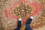 Detail of rococo medallion and soft patina on a faded cherry red Anatolian rug.