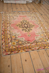 Side view of a Vintage Anatolian rug, showcasing its gold diamond border and faded red field of rococo leaves.