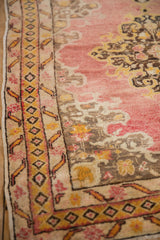 Vintage Anatolian rug's geometric gold border, finial motifs, and faded red rococo leaves.