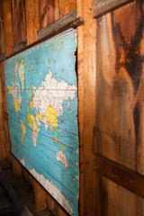 Lower right of vintage world map, blue ocean, Antarctica, wooden dowel, and torn edge.