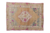 Vintage distressed Oushak rug with a stepped medallion and corner spandrels in dusty gold, fuchsia, and teal.